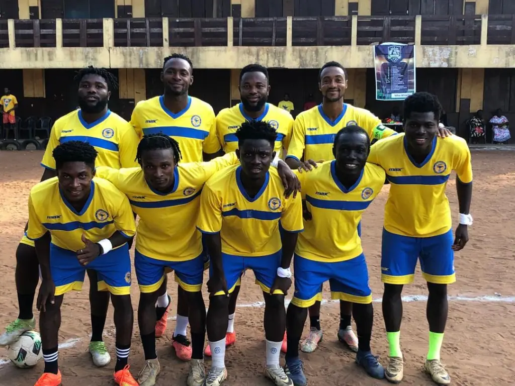 Nine players in yellow and blue kits posing together as a team